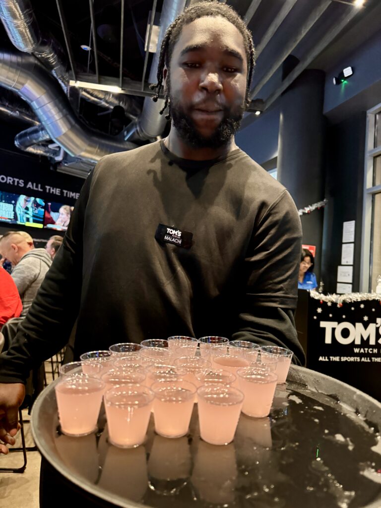 Server serving shots to customers at Tom's Watch bar